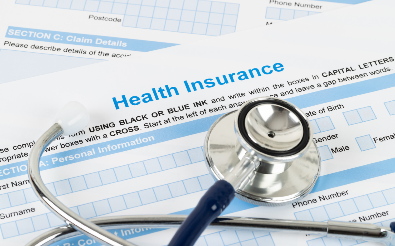A Stethoscope Rests On Top Of Health Insurance Claim Forms, Highlighting The Connection Between Medical Care And Insurance Paperwork. A Stethoscope Rests On Top Of Health Insurance Claim Forms, Highlighting The Connection Between Medical Care And Insurance Paperwork.
